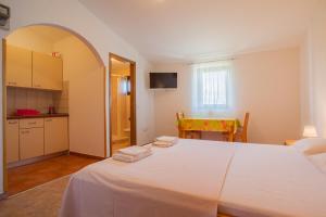 a bedroom with a large white bed and a kitchen at Apartments Dandić in Orlec
