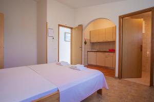 a bedroom with a white bed and a kitchen at Apartments Dandić in Orlec