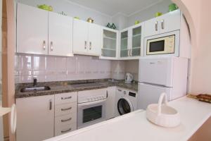 uma cozinha com armários brancos e uma máquina de lavar e secar roupa em CAPISTRANO PLAYA 512 MENYBER em Nerja