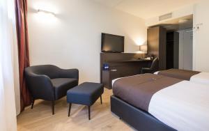 a hotel room with a bed and a chair and a tv at Bastion Hotel Bussum Hilversum in Bussum