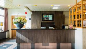 a lobby with a reception counter with a vase of flowers at Bastion Hotel Bussum Hilversum in Bussum