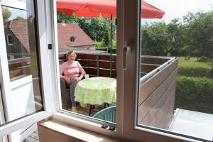 a woman sitting at a table on a balcony at Ferienwohnung Rabenstein in Dornum