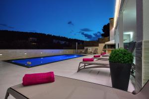 a patio with a pool and some chairs and a table at Apartments Villa Katija in Drvenik