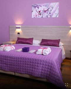 a purple bedroom with a purple bed with towels on it at Policlinico Happy Home in Messina