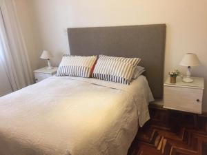 una camera con un letto bianco con due comodini di Departamentos de Buen Nivel a Mendoza