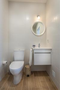 a white bathroom with a toilet and a mirror at Raminhos Guest House in Vila Nova de Milfontes