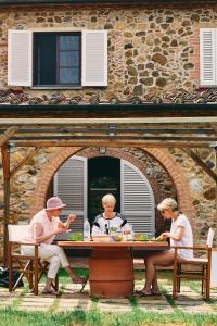 een groep van drie personen die aan een tafel zitten bij Poggio Cornetto in Bibbona