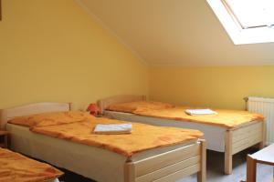 2 camas en una habitación con paredes amarillas en Király Szálló & Panzió en Nagykanizsa