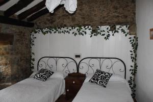 two twin beds in a room with a wall at Casa Rural Las Machorras I y II in Bárcenas