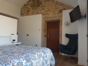 a bedroom with a bed and a chair and a television at Desconectate in Aldán