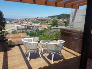 a balcony with three chairs and a view of a city at Desconectate in Aldán