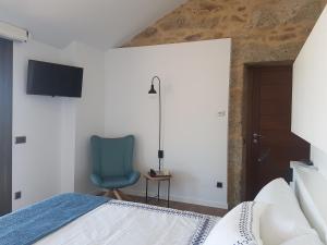 a bedroom with a bed and a blue chair at Desconectate in Aldán