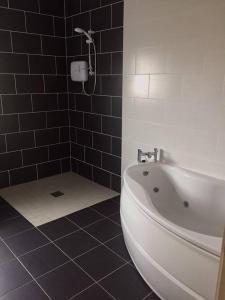 a bathroom with a white tub and black tiles at Leghowney House in Donegal