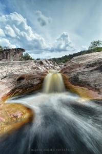 a waterfall on a rocky hillside with water rushing down it at Camping Permacultural Filhos da Floresta in Vale do Capao