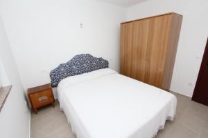 a bedroom with a white bed and a wooden cabinet at Apartment Mihaela in Rovinj