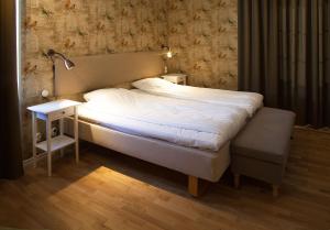 a bed in a room with a lamp and a night stand at Södra Hotellet in Norrköping