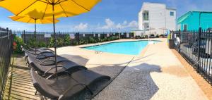a row of benches with an umbrella next to a pool at Four Seasons on the Gulf in Galveston