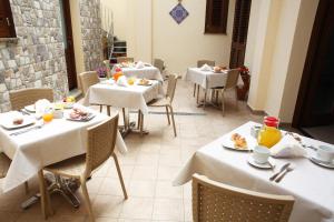 a restaurant with white tables and chairs with food on them at Ninni e Fede in San Vito lo Capo