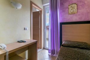 a bedroom with a bed and a window with purple curtains at Hotel Rubens in Rimini