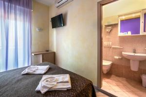 a bathroom with a bed and a sink and a toilet at Hotel Rubens in Rimini