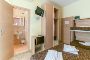 a room with two beds and a bathroom with a sink at Hotel Rubens in Rimini