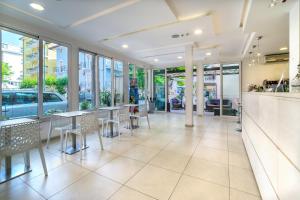 a restaurant with tables and chairs and windows at Hotel Rubens in Rimini