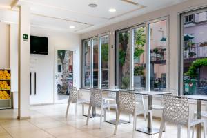 a dining room with tables and chairs and windows at Hotel Rubens in Rimini