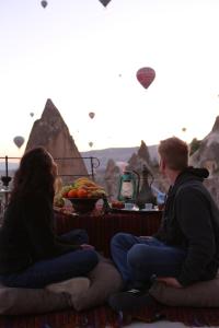 a man and a woman sitting next to a table with kites at Village Cave House Hotel in Göreme