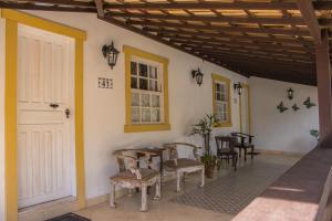 a porch with chairs and a table and a door at Pousada Hospedaria da Villa in Tiradentes