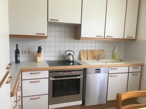 a kitchen with white cabinets and a stove and a sink at Karls Ferienwohnung mit Terrasse in Teufenbach