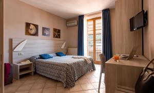 a bedroom with a bed and a desk with a laptop at Hotel Corallo in Pomonte