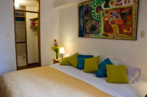 a bedroom with a bed with green and blue pillows at Casa de Baraybar in Lima