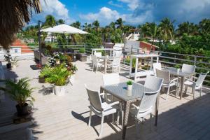 un patio con mesas blancas, sillas y palmeras en Art Villa Dominicana, en Punta Cana