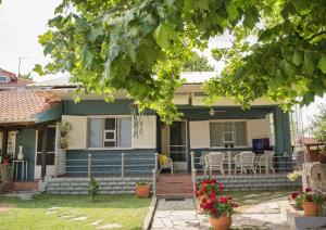 a blue house with a porch with a table and chairs at Seaside Cottage in Paralia Katerinis