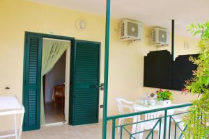 Zimmer mit grüner Tür, Tisch und Balkon in der Unterkunft Villaggio Turistico Defensola in Vieste