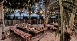 un grupo de mesas de madera con bancos y palmeras en Campo Bahia Hotel Villas Spa en Santo André