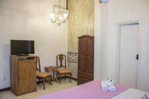 a bedroom with a bed and a tv and a chair at Pousada Hospedaria da Villa in Tiradentes