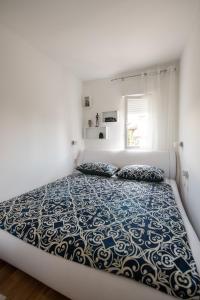 - une chambre blanche dotée d'un grand lit avec des draps bleus et blancs dans l'établissement Apartment Emili, à Opatija