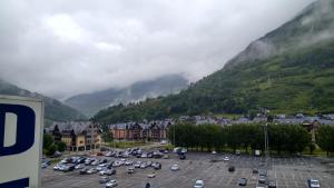 a parking lot with cars parked in front of a mountain at Hotel Delavall in Vielha