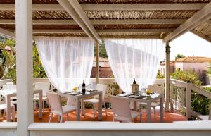 a patio with white tables and chairs on a porch at Hotel Corallo in Pomonte