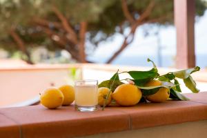 a pile of oranges on a table with a glass of orange juice at Hotel Corallo in Pomonte