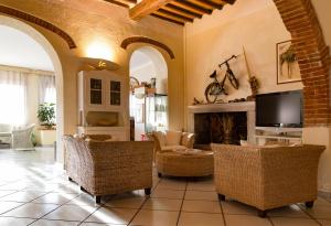 a living room with a fireplace and chairs and a tv at Hotel Corallo in Pomonte