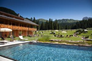 a large swimming pool in front of a building at Dolomites Living Hotel Tirler in Alpe di Siusi