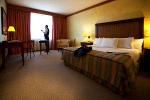 una habitación de hotel con una cama y un hombre parado en una ventana en Park Hotel Calama, en Calama