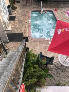a swimming pool with a red umbrella and a table at New Orleans House - Gay Male-Only Guesthouse in Key West