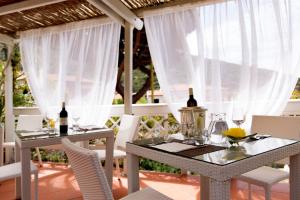 two tables with wine bottles and chairs on a patio at Hotel Corallo in Pomonte