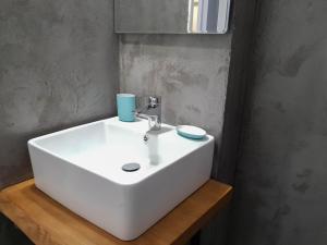a white bathroom sink with a blue cup on it at Vathy Studios in Meganisi