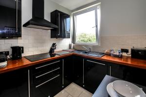 a kitchen with black cabinets and a sink and a window at Apartment F in Aberdeen