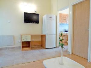 a room with a white refrigerator and a table with a vase at Apartments Mladen in Njivice