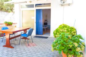 un patio con una mesa de madera, sillas y una planta en Apartments Paunovic, en Makarska